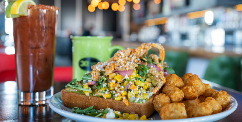 Open faced breakfast sandwich with tater tots and a bloody mary
